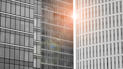 Fototapeta na wymiar Modern architectural details. Modern glass facade with a geometric pattern. Contemporary corporate business architecture. Red sun on horizon. Black and white toned image.