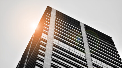 Obraz premium Modern architectural details. Modern glass facade with a geometric pattern. Contemporary corporate business architecture. Red sun on horizon. Black and white toned image.