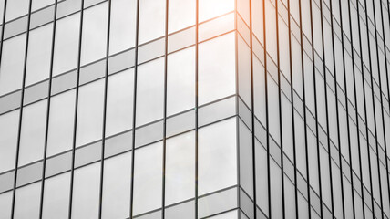 Modern architectural details. Modern glass facade with a geometric pattern. Contemporary corporate business architecture. Red sun on horizon. Black and white toned image.