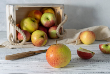 Yellow-red apples in a wooden box on a light napkin