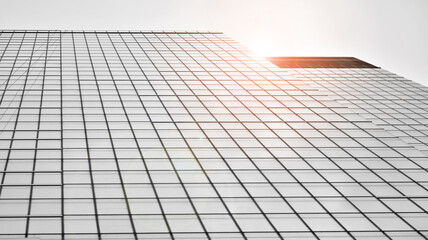 Modern architectural details. Modern glass facade with a geometric pattern. Contemporary corporate business architecture. Red sun on horizon. Black and white toned image.
