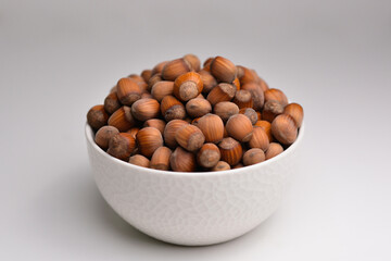 Organic hazelnut. Full bowl of hazelnuts in bowl. Hazelnut in white bowl isolated on white background.