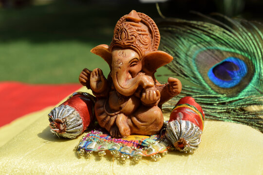 Beautiful lord Ganesha idol worshipped during Ganesh chaturthi festival with peacock feather in background. Sitting Ganpati with pillows and bolsters during Vinayaka chavithi