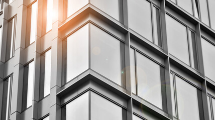 Modern architectural details. Modern glass facade with a geometric pattern. Contemporary corporate business architecture. Red sun on horizon. Black and white toned image.