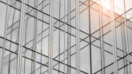 Modern architectural details. Modern glass facade with a geometric pattern. Contemporary corporate business architecture. Red sun on horizon. Black and white toned image.