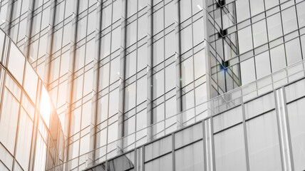 Obraz premium Modern architectural details. Modern glass facade with a geometric pattern. Contemporary corporate business architecture. Red sun on horizon. Black and white toned image.