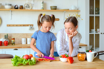 Obraz na płótnie Canvas mom and daughter cook healthy food together in the kitchen. healthy food and lifestyle concept