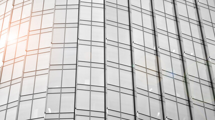 Fototapeta premium Modern architectural details. Modern glass facade with a geometric pattern. Contemporary corporate business architecture. Red sun on horizon. Black and white toned image.
