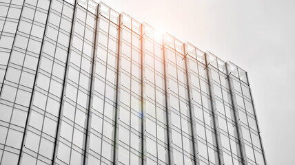 Fototapeta premium Modern architectural details. Modern glass facade with a geometric pattern. Contemporary corporate business architecture. Red sun on horizon. Black and white toned image.