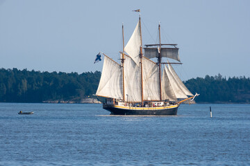 Fototapeta na wymiar An old schooner with rised sails sailing across the horizon.