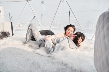 Woman lying on her man and laughing while her man kissing her cheek