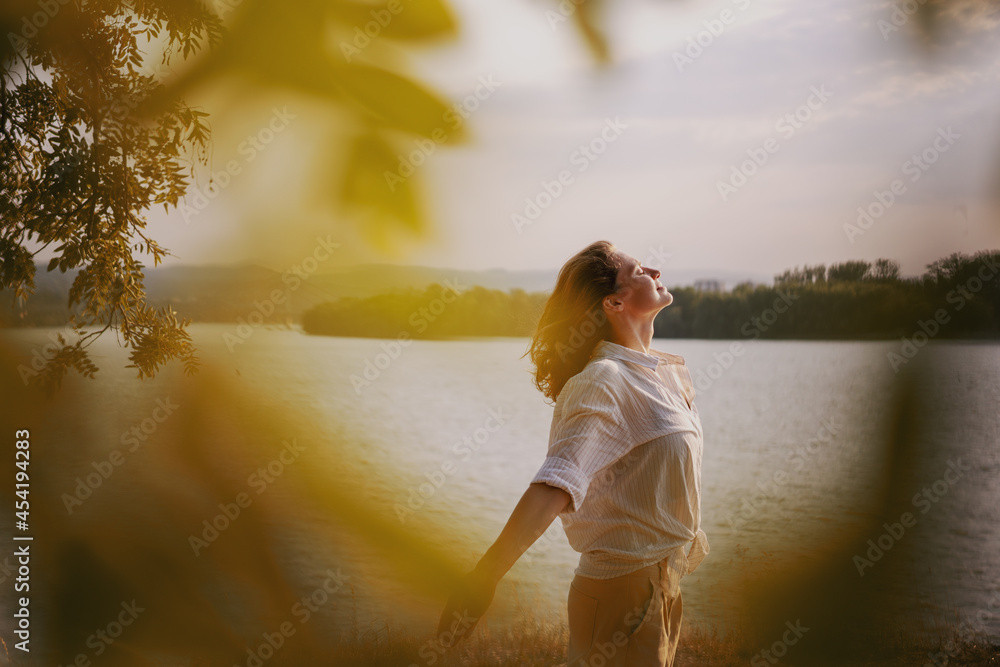 Wall mural beautiful young relaxed woman in white blouse enjoying nature breathing fresh air meditating on the 