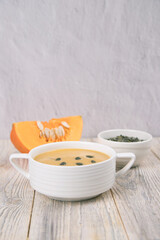 Pumpkin puree soup on a light wooden background. Copy space
