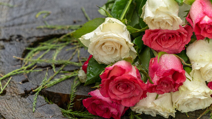 Bouquet of roses, white and pink, placed on a large tree stump near the lake, on a rainy day, close up
