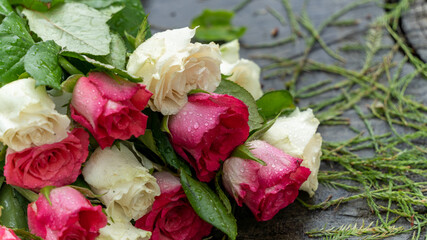 Fototapeta premium Bouquet of roses, white and pink, placed on a large tree stump near the lake, on a rainy day, close up