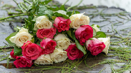 Bouquet of roses, white and pink, placed on a large tree stump near the lake, on a rainy day, close up