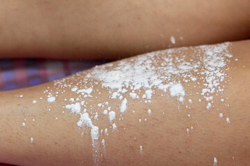 Fototapeta premium Depilation of the lower leg.Removal of unnecessary leg hair in a beauty salon.Preparation and degreasing of the skin before epilation.A white sprinkle is applied to the skin of the legs