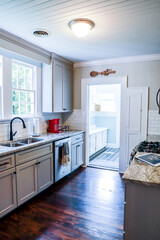 A small cottage kitchen with gray cabinets and dark hardwood floors in a short-term rental house