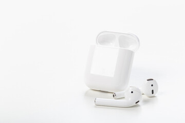 Modern wireless bluetooth earphones with charging case on a light gray background. The concept of...