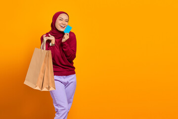 Happy pretty excited shopper showing a credit card. holding bags and smiling
