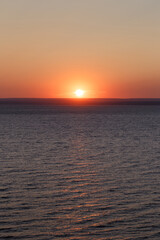 Beautiful colorful sunset over the sea. The red sun and the absence of clouds. Sea horizon. Aerial view. Landscape. The concept of a postcard picture. Light waves on the sea surface