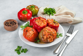 A plate with stewed stuffed peppers with fresh herbs on a gray background. Side view, close-up.