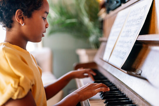 Musical education. Happy black girl playing the piano