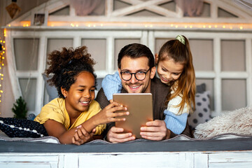 Multiethnic children and father having fun, playing on tablet at home