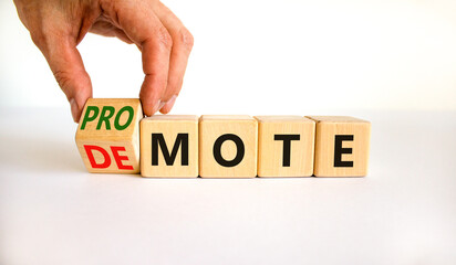 Promote or demote symbol. Businessman turns a cube and changes the word 'demote' to 'promote'. Beautiful white table, white background. Business, demote or promote concept. Copy space.