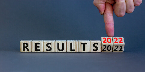 2022 results new year symbol. Businessman turns a wooden cube and changes words 'results 2021' to 'results 2022'. Beautiful grey background, copy space. Business, 2022 results new year concept.