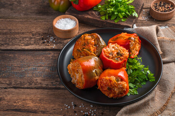 Homemade, stewed Bulgarian pepper stuffed with meat, rice and vegetables on a wooden background. Side view, space for copying.