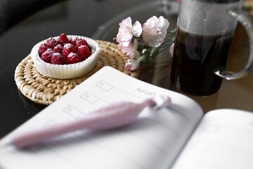 Rapberry tart and the coffee on the table with open notebook