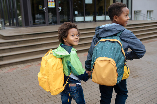 Little Boys With Back Packs. Two African American Boys Next To The School. Back To The School Concept. Kids Standing Outside And Happy To Meet Each Others. Happy Black Children. First Day Of School