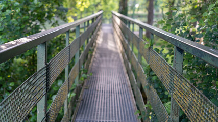 Metal footbridge crossing the river among the trees, close-up	