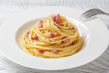 Spaghetti carbonara in a white plate. Spaghetti, pancetta and sauce made of egg yolk and parmesan...