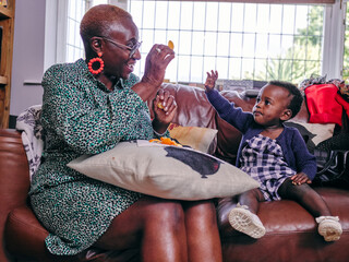 Grandmother giving food to granddaughter - Powered by Adobe