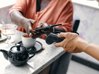 UK,ÊClose-upÊof woman paying with smart phone at cafe table