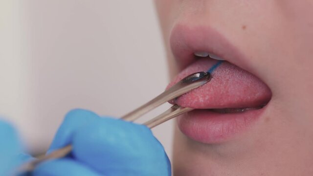 Close up portrait of young Caucasian woman sticking out pierced tongue.