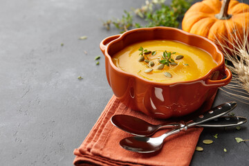 Pumpkin soup with thyme and pumpkin seeds on black background