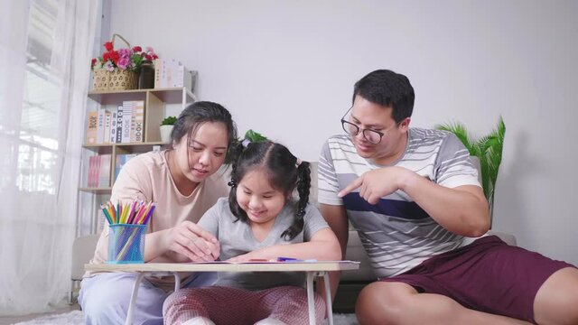 Happy fat Asian family spending time to paint on  paper and talk in living room. Painting with color pencil in living room at home. Happy fat family on the weekend at home