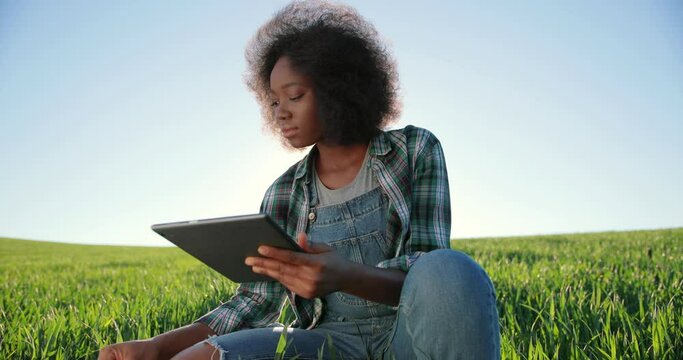 Motion camera view of the optimistic multiracial female farmer scientist using tablet computer technology application while working at the field and smiling. Agriculture concept