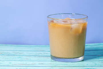 milk pour in glass of iced coffee on blue background