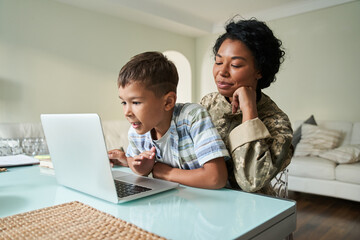 Black mother and son watching something on laptop