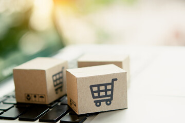 Shopping online. Cardboard box with a shopping cart logo on laptop keyboard. Shopping service on The online web. offers home delivery. copy space.