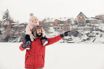 Handsome bearded young dad and his little cute daughter are having fun outdoor in winter. Enjoying spending time together. Family concept