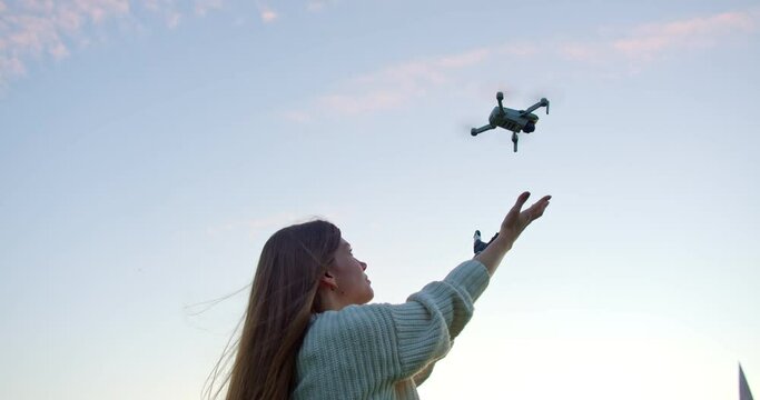 A young woman reaches out with a bionic hand to a drone to land it on a robotic hand. The quadcopter descends, the girl catches it with a bioelectric artificial brush. the introduction of modern