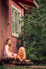 Two sisters are eating berries sitting on the wooden porch of their dacha house. Image with selective focus and toning
