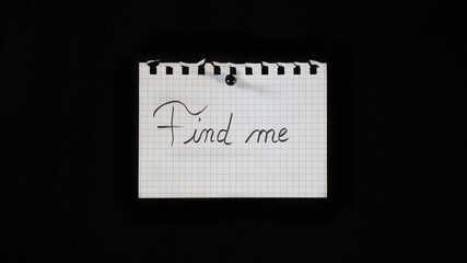 Hand written message on a ripped notebook sheet, "Find me"	