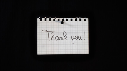 Hand written message on a ripped notebook sheet, "Thank you"	