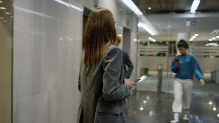 Business woman exiting elevator in office. Female executive walking in lobby